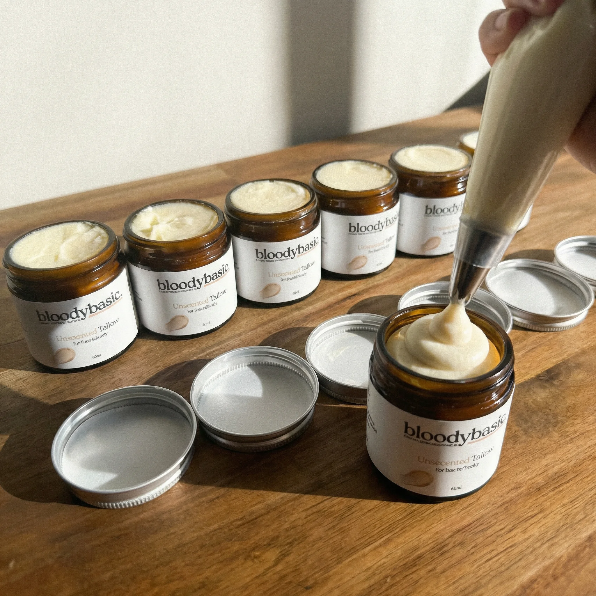 Bloody Basic tallow balm being piped into amber glass jars during production